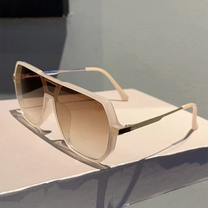 Detail view of cream-colored aviator sunglasses with gradient brown lenses and gold metal temples