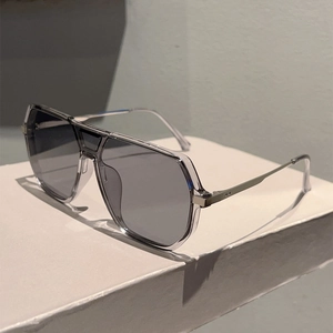 Detail of pilot sunglasses featuring a transparent grey frame and silver metal accents