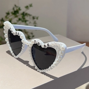 Detail der weißen Herz-Sonnenbrille mit Perlen und Bride To Be Schriftzug am Rahmen