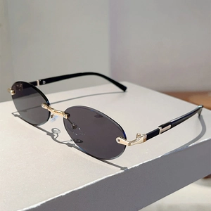 Detailed view of rimless oval sunglasses with grey lenses and gold metal nose bridge