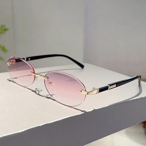 Detail view of rimless oval sunglasses with gradient pink lenses and gold metal bridge
