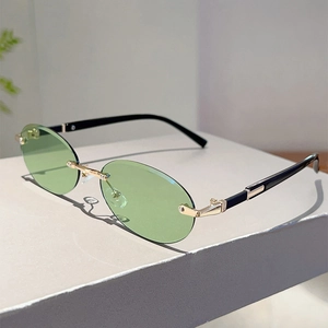 Detailed side view of rimless oval sunglasses with green lenses and gold metal temples