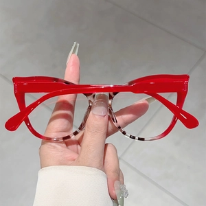 Detail of red and tortoiseshell cat-eye glasses frame held by hand showing split-color design