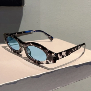 Detail of tortoiseshell oval sunglasses with blue lenses on a white display stand
