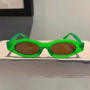 Detail of neon green transparent cat-eye sunglasses with oval brown tinted lenses