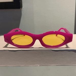Close-up of retro narrow cat-eye sunglasses with rose red frames and yellow lenses