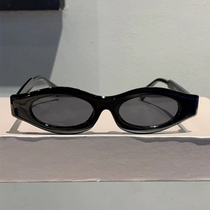 Detail view of bold black oval sunglasses with glossy frames and dark grey lenses