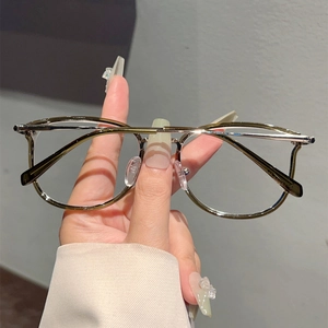 Detail of vintage metal frame glasses with olive green rims and gold-tone bridge