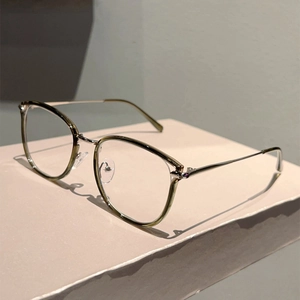 Detail view of stylish olive green frames with slim silver metal temples on a pink stand