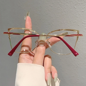 Détail des lunettes œil-de-chat légères en métal doré avec des accents rouges et verres clairs