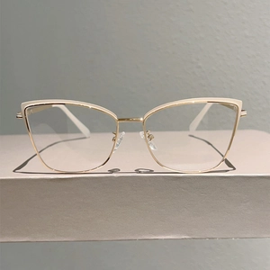 Détail de lunettes œil-de-chat avec bord crème et branches fines en métal doré