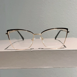Monture de lunettes œil-de-chat en métal doré et noir montrant les plaquettes de nez et branches