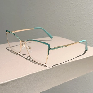 Détail de la monture de lunettes œil de chat en métal doré et bleu cyan sur fond sobre