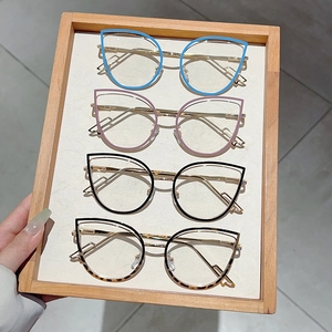 Close-up of assorted cat-eye eyeglass frames with gold metal temples on a wooden tray