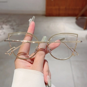Detailed close-up of golden metal cat-eye glasses frame with hollow-out wave design