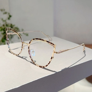 Cat-eye glasses detail showing gold metal frame with leopard print accents on grey stand