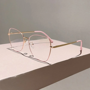 Close-up of pink cat-eye frames with golden metal temples and smooth geometric shadows