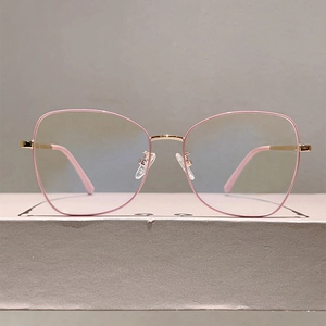 Detailed view of pink and gold metal eyeglass frames with soft nose pads and clear lenses