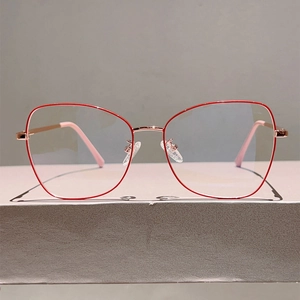 Detailed close-up of red and rose gold polygonal metal optical frames with nasal pads