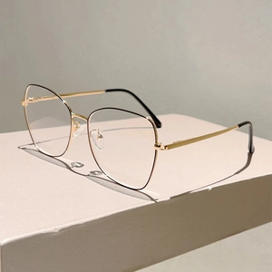 Retro cat-eye metal blue light blocking glasses in gold finish on a minimalist stand