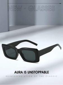 Classic thick black square frame sunglasses with grey lenses in an architectural setting