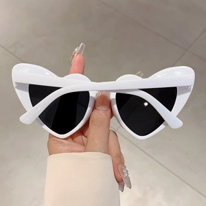 Close-up of white heart-shaped sunglasses with thick frames and dark lenses