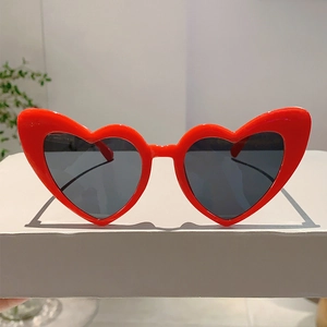 Macro detail of red heart-shaped sunglasses frame with dark protective lenses