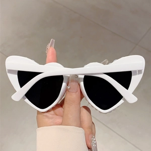 Detail view of heart-shaped white sunglasses with pearl beads and dark lenses