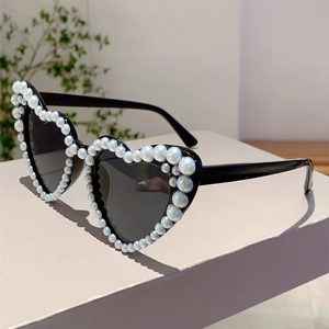 Detailed side view of heart-shaped sunglasses featuring black frames and faux pearl embellishments