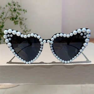Detailed close-up of heart-shaped sunglasses with inlaid pearls on black frames
