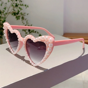Detail of pink heart-shaped sunglasses featuring white pearls and gradient purple lenses