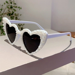 Close-up of heart-shaped sunglasses with pearl-embellished frames and dark lenses