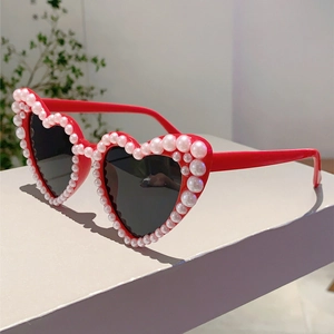 Detail of red heart-shaped sunglasses with pearl-embellished frames and dark lenses