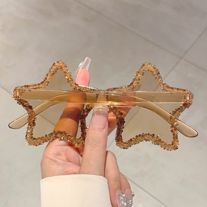 Close-up of star-shaped sunglasses featuring handcrafted rhinestones and champagne lenses