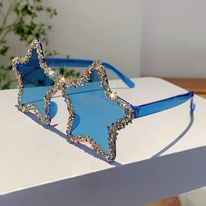 Close-up of star-shaped blue sunglasses with colorful rhinestones on a white pedestal