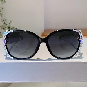 Detail einer schwarzen Oversize-Sonnenbrille mit edlem Strassbesatz am Rahmen für Damen