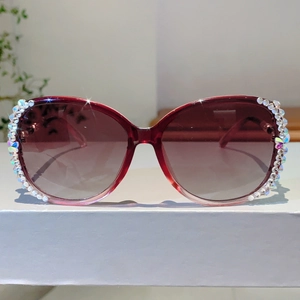 Detail der burgunderfarbenen übergroßen Sonnenbrille mit glitzerndem Strassbesatz am Rand