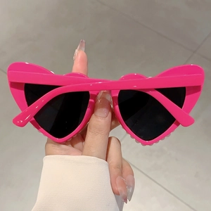 Close-up of bright pink heart-shaped sunglasses with a glossy finish and dark lenses