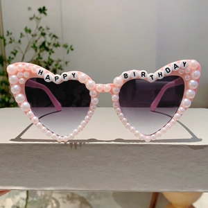 Detail of pink heart-shaped birthday sunglasses with pearl rim and happy birthday text
