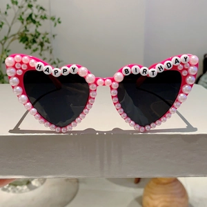 Detail of pink heart-shaped party sunglasses with pearls and Happy Birthday text