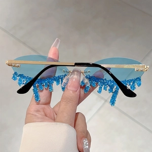 Detail of blue crystal teardrop embellishments on rimless gold metal sunglasses