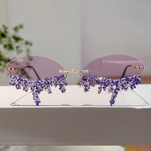 Close-up of rimless sunglasses with purple lenses and teardrop rhinestone fringe detail