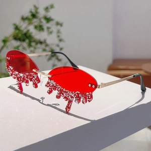 Close-up of red rimless sunglasses with teardrop lenses and sparkling rhinestone accents