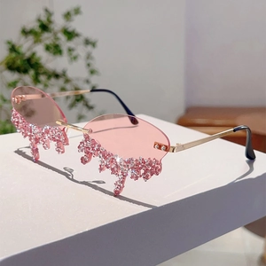 Close-up of rimless pink sunglasses with crystal teardrop tassels and gold frame