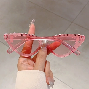 Détail de lunettes de soleil œil-de-chat roses avec perles et lettrage Queen pour fête