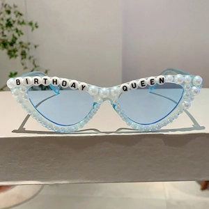 Détail de lunettes de soleil œil-de-chat bleu clair avec lettrage Queen et perles blanches