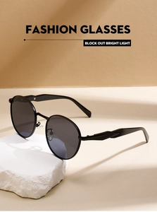 Close-up of black round metal sunglasses on a white stone base with soft natural shadows
