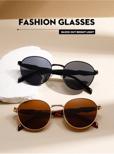 Detail of round metal frame sunglasses in black and vintage gold with dark lenses