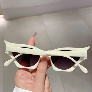 Détail de lunettes de soleil œil de chat blanc crème avec monture ailée unique