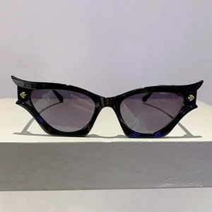 Détail de lunettes œil-de-chat noires avec logo doré et verres teintés violets